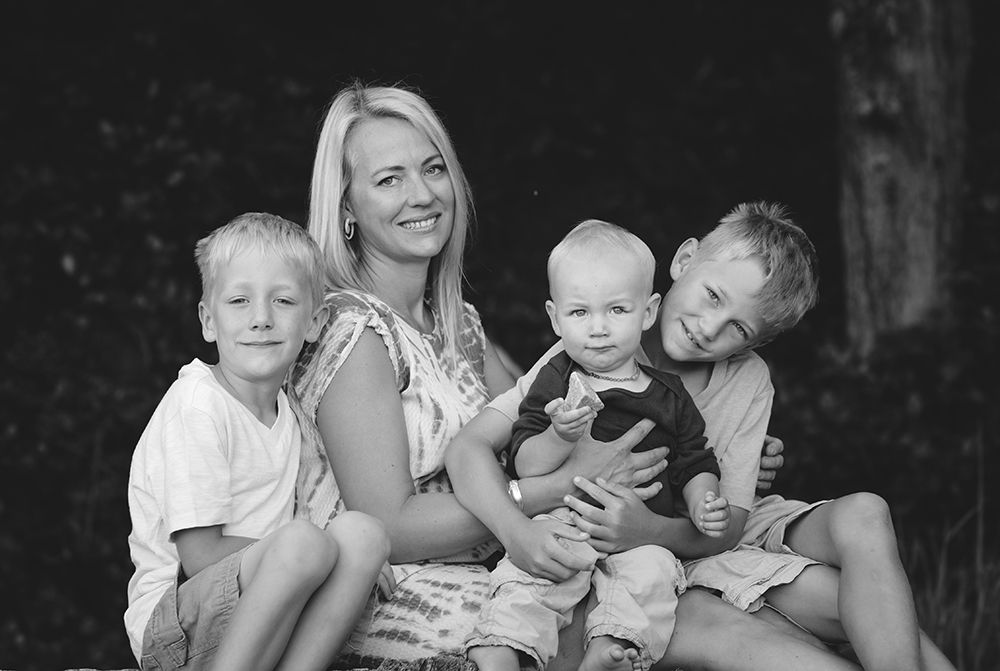 Black and white portrait of family members laughing together outdoors.