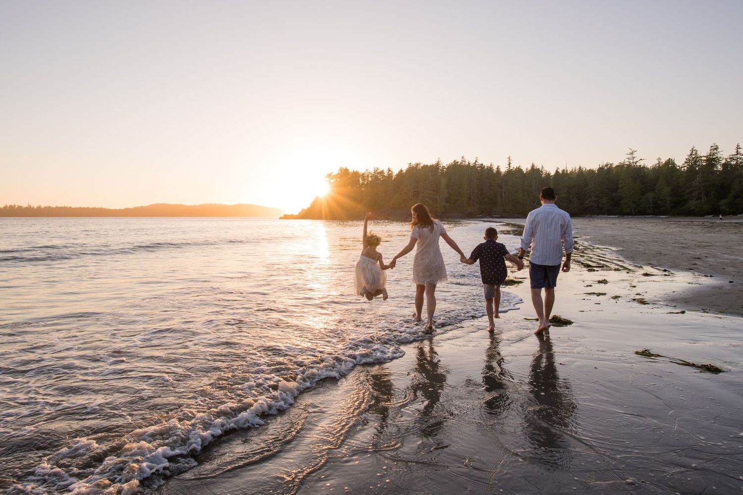 A family walks along a scenic beach at sunset, creating silhouettes against the golden sky.