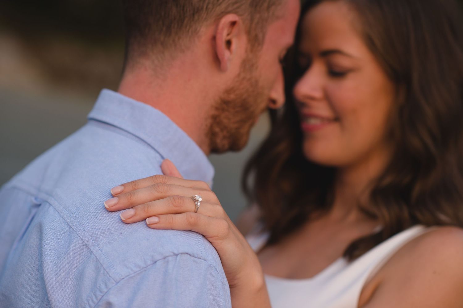 A couple shares an intimate moment together against a bright background.