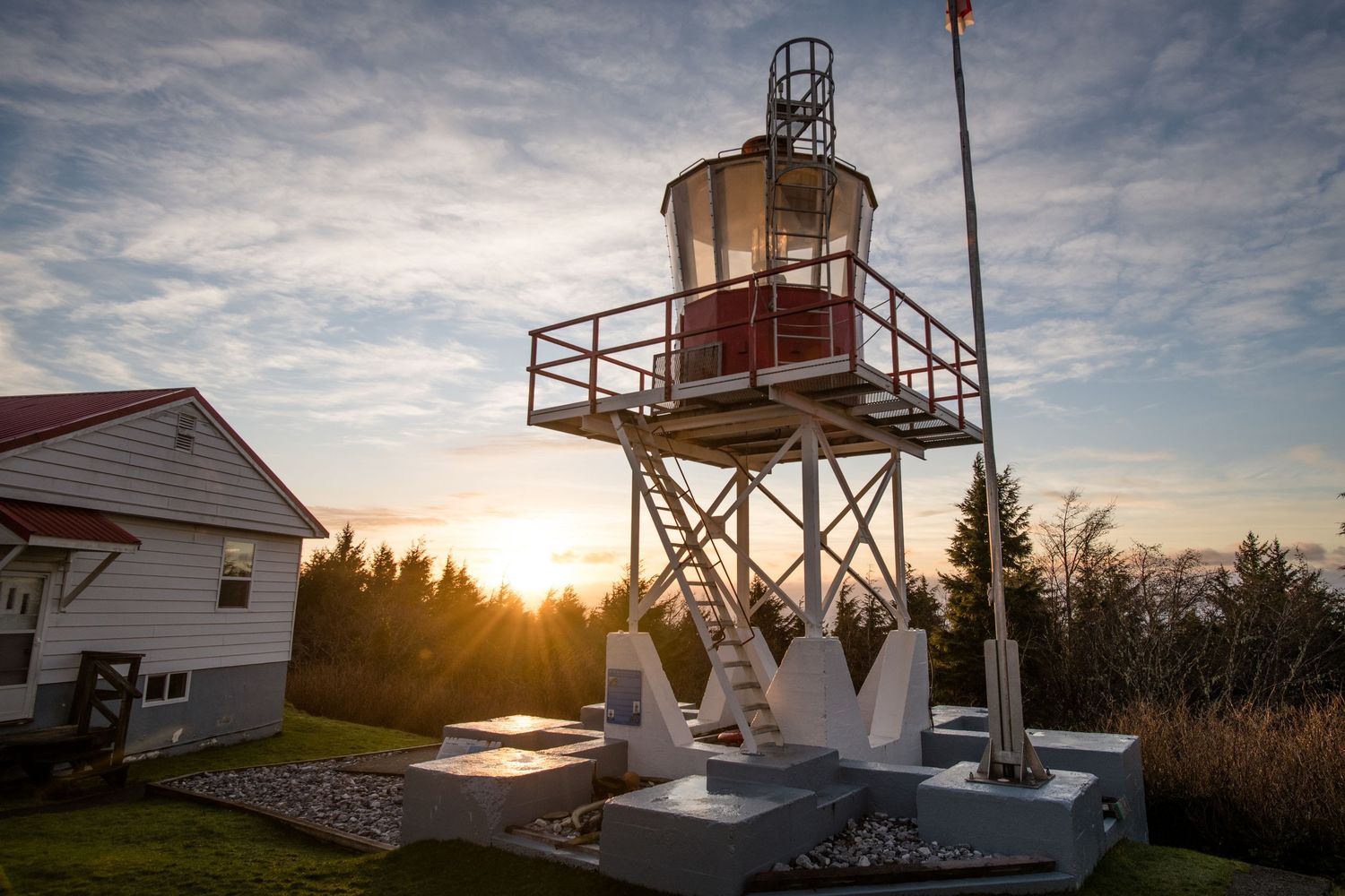 Lighthouse station silhouettes against colorful sunset sky with multiple structures and observation towers.
