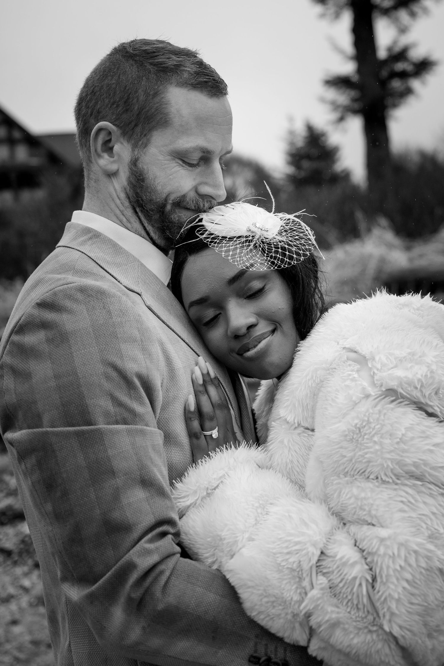 An intimate black and white portrait of a couple embracing while wearing wedding attire.