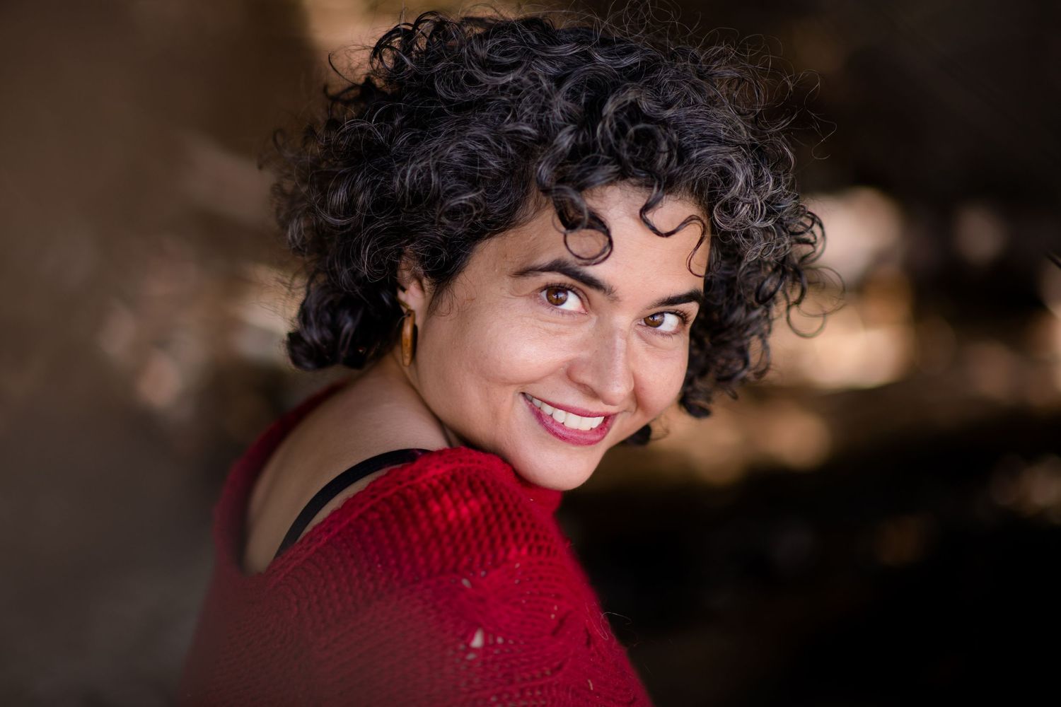 Cozy winter portrait in red sweater against dark background.