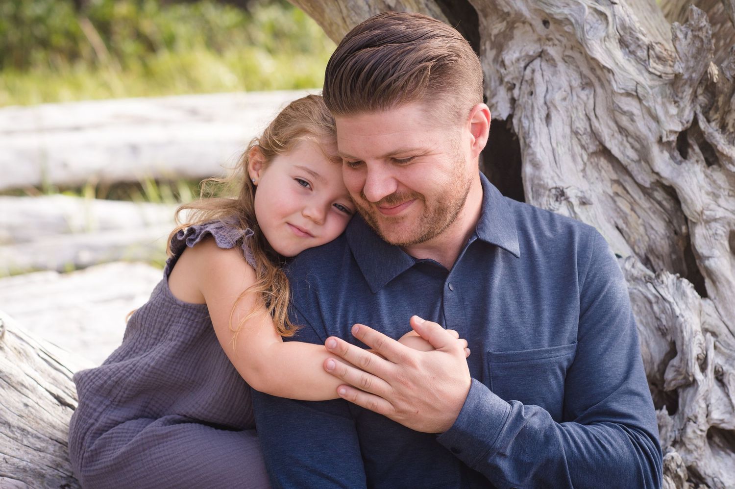 Intimate family moments captured against coastal driftwood backdrop.
