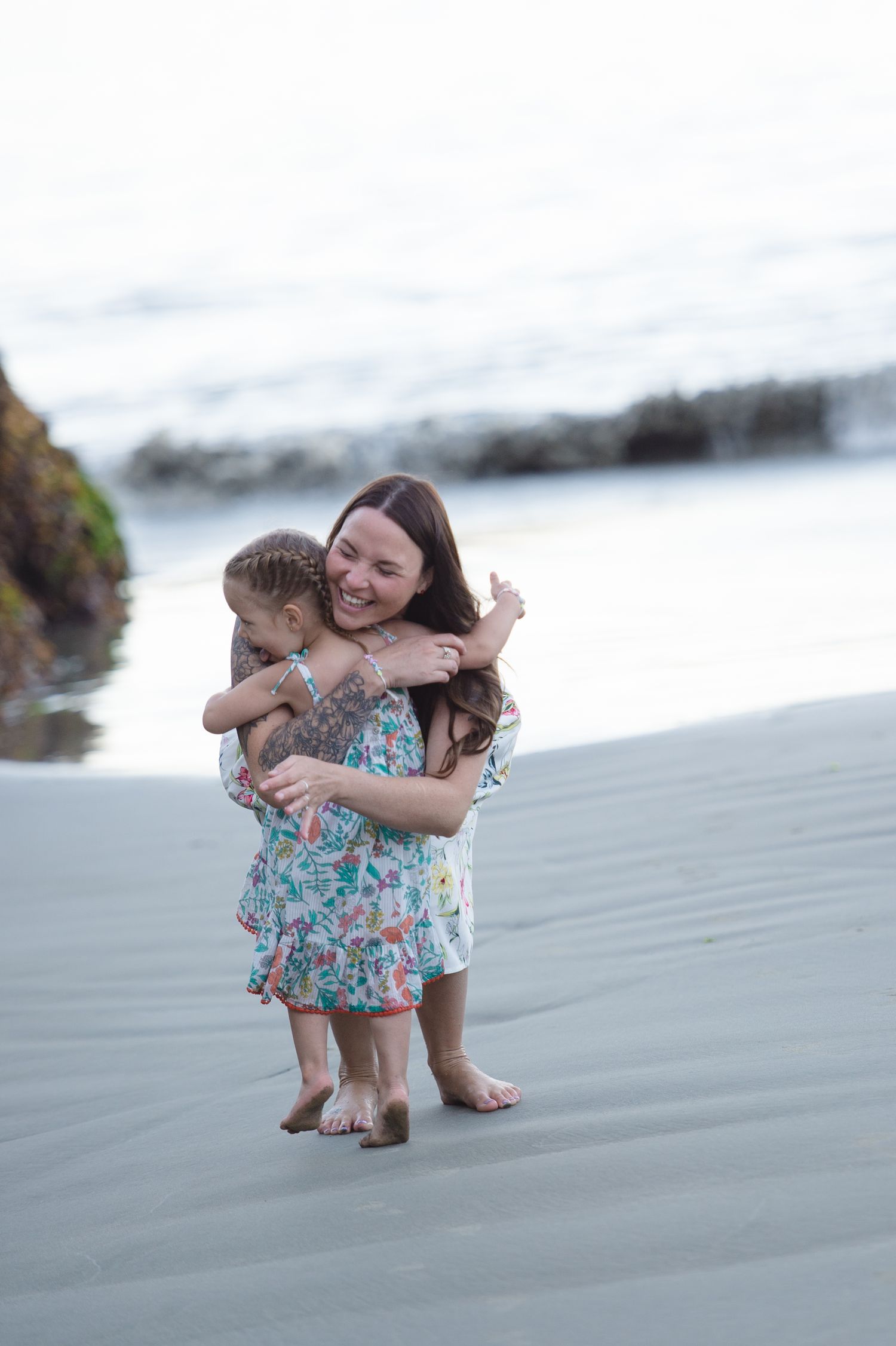 Sweet embraces shared during a beach photoshoot with matching floral dresses.
