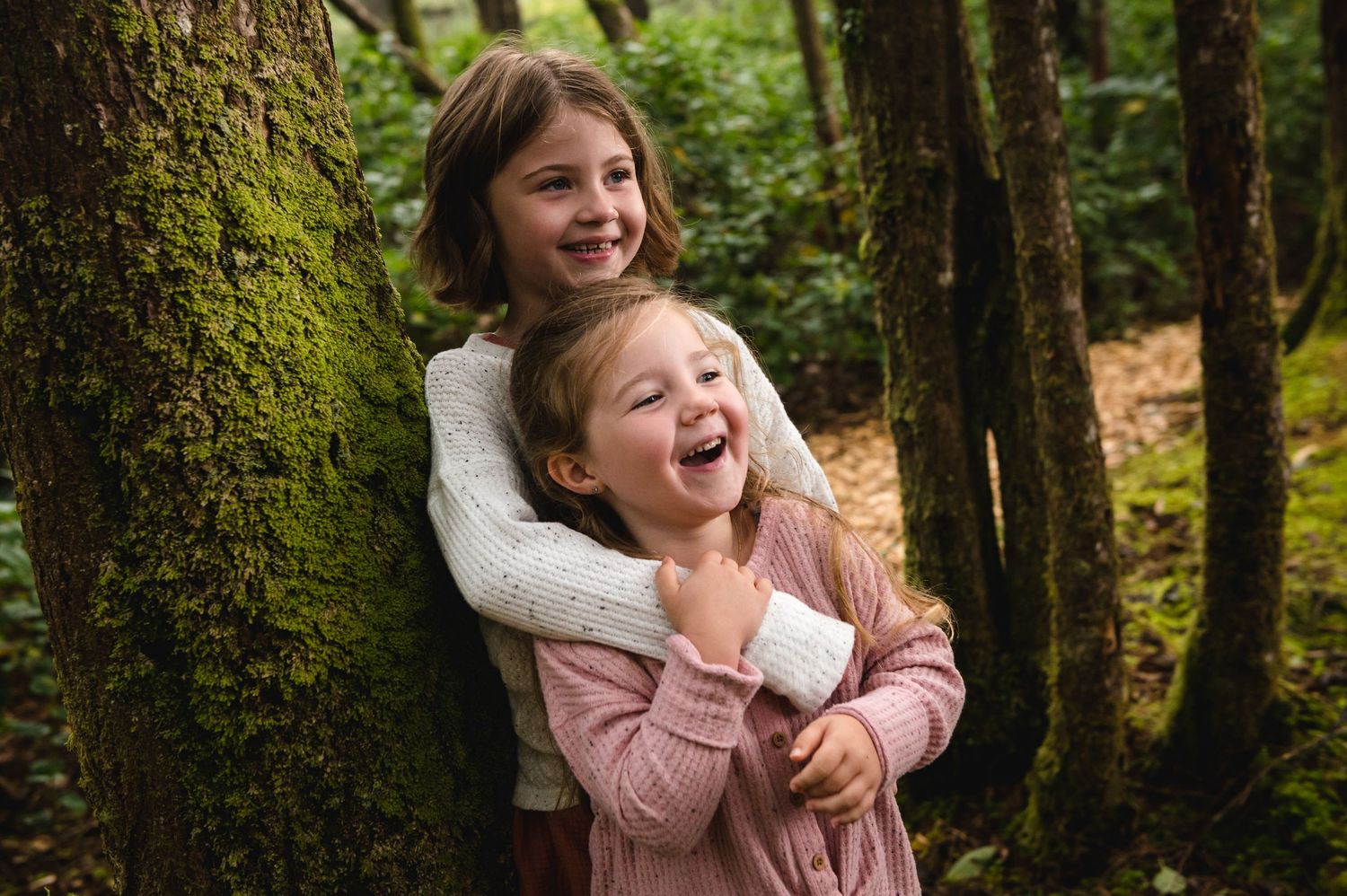 Child playing joyfully in a lush green forest setting.