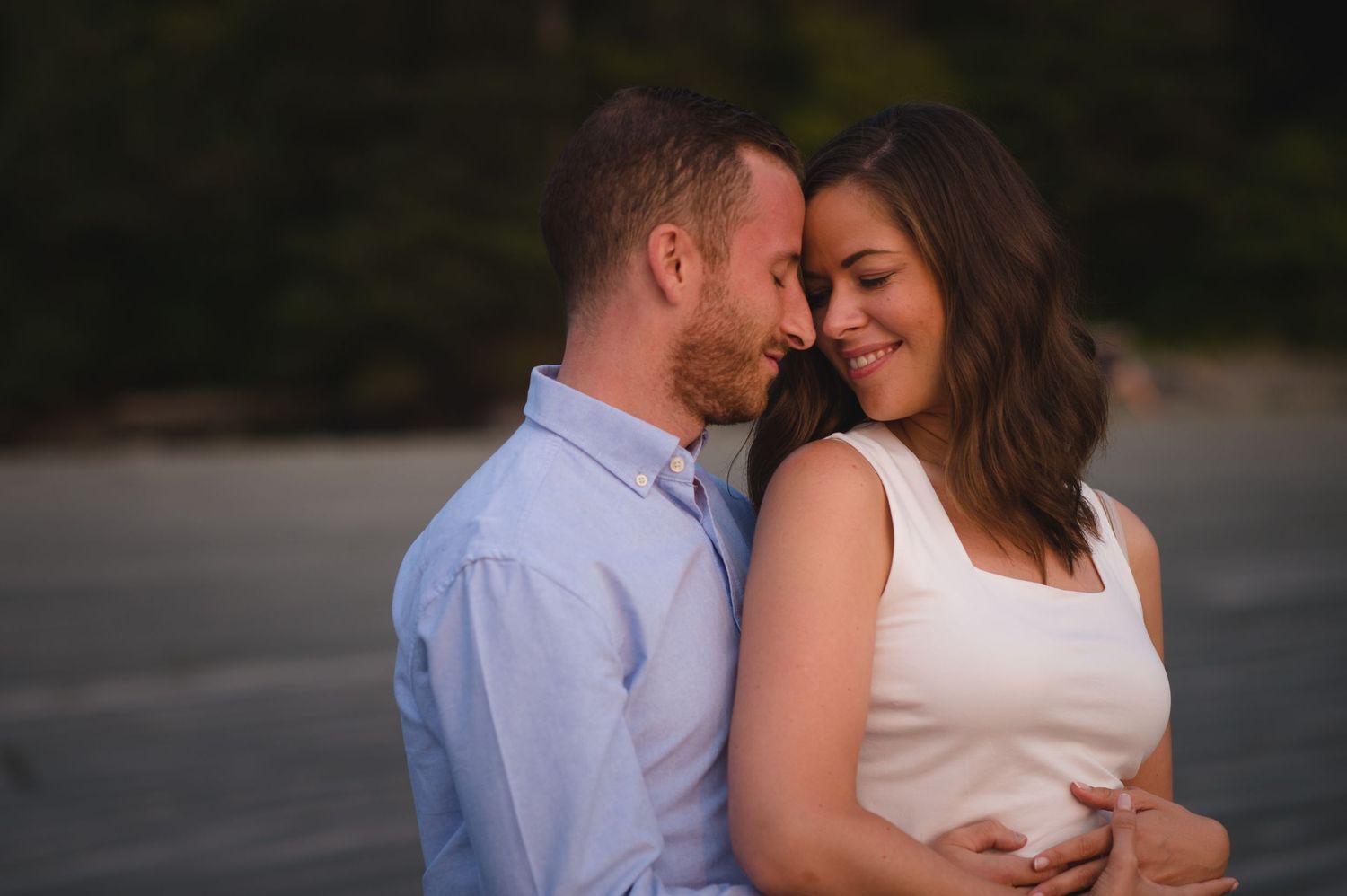 Intimate couple shares tender moment against natural outdoor backdrop.