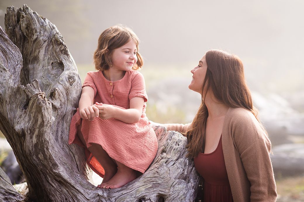 Mother and child share joyful moments together while sitting in a tree at sunset.