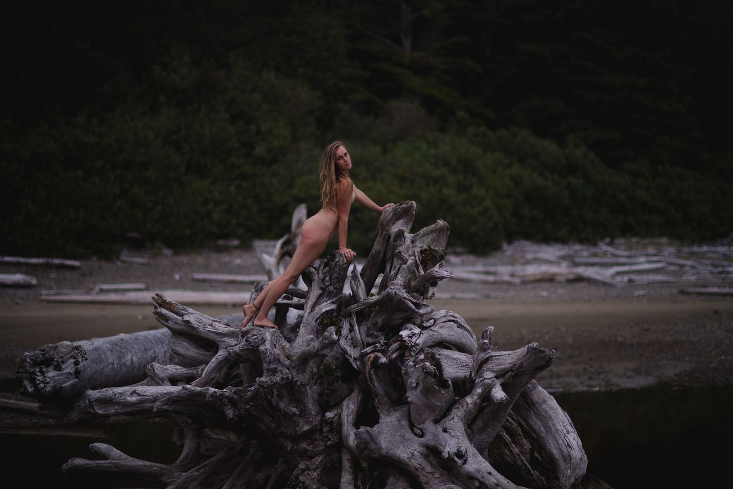 A person splashes through water on a rocky beach while riding a dirt bike motorcycle.