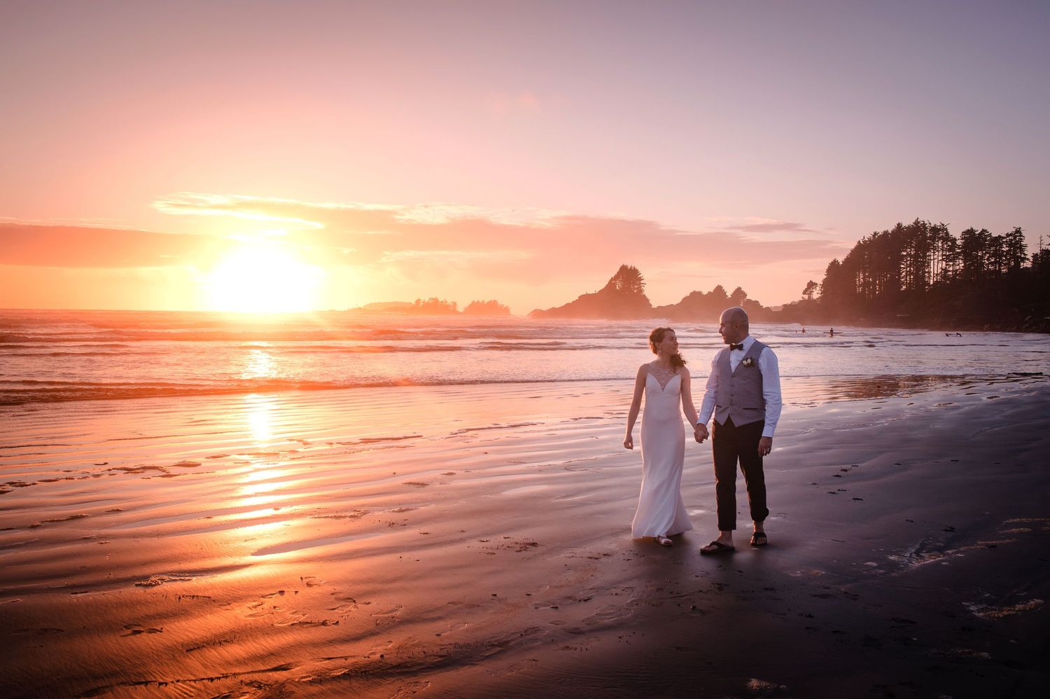 Golden sunset over a beach with silhouettes walking along the shore.