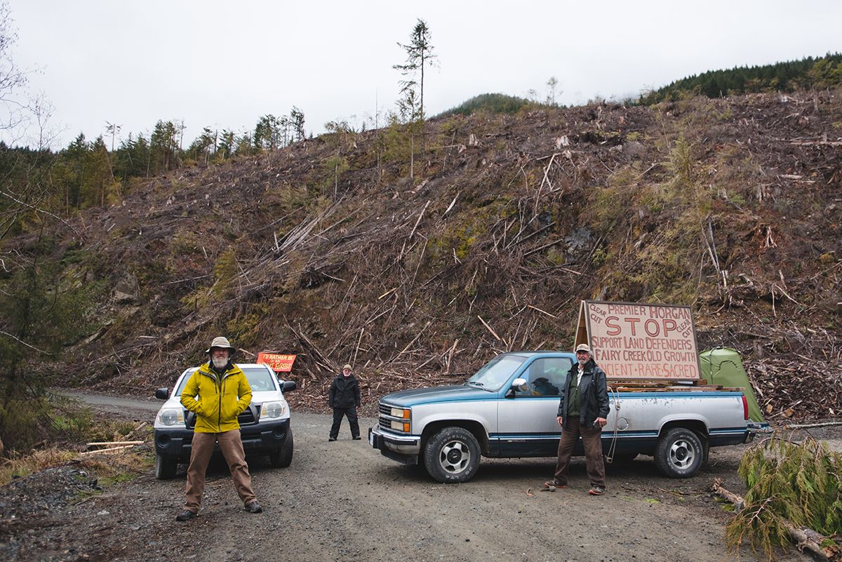 Fairy Creek blockade. Logging protest site with vehicles and signs on a dirt road.