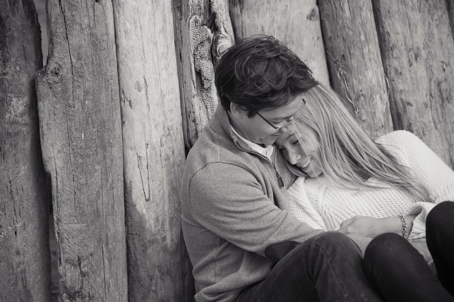 Black and white intimate portrait against rustic wooden wall backdrop.