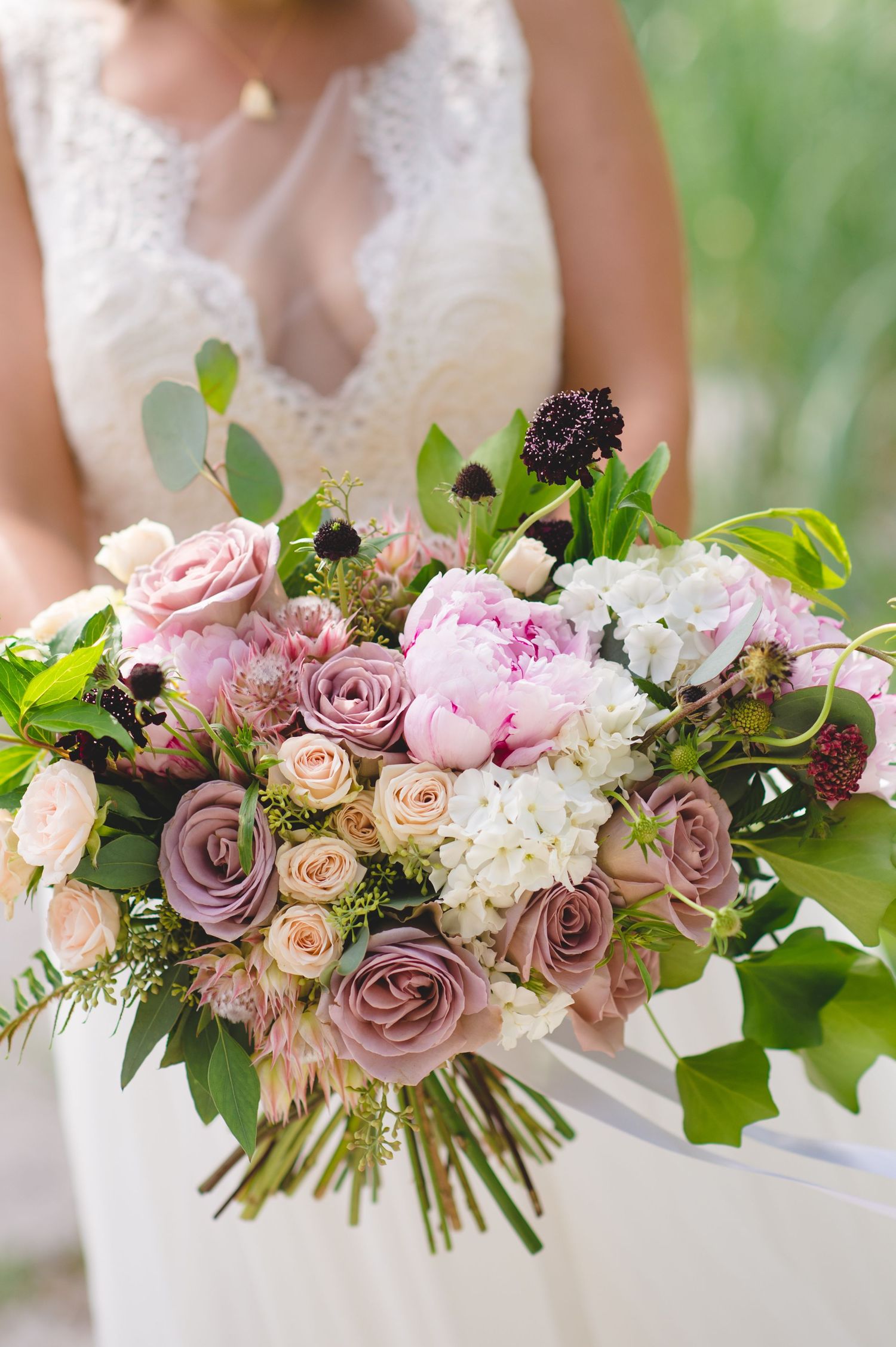 Beautiful wedding bouquet with pink and mauve roses, white hydrangeas and greenery arranged in a loose romantic style.