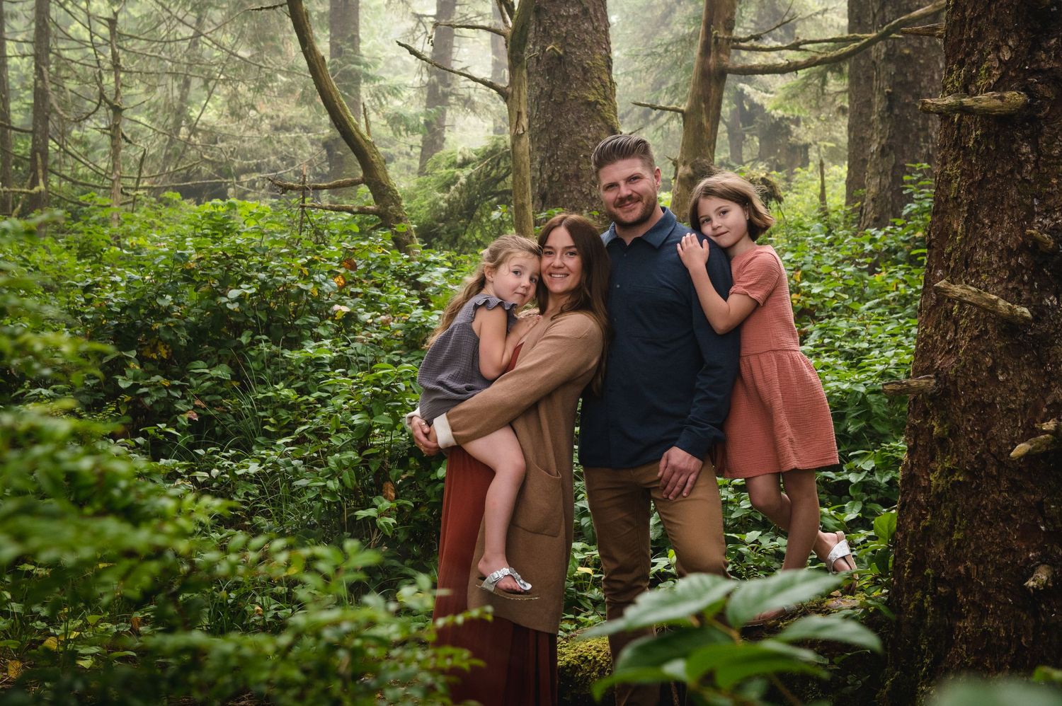 Casual family photoshoot among tall trees in a peaceful forest setting.