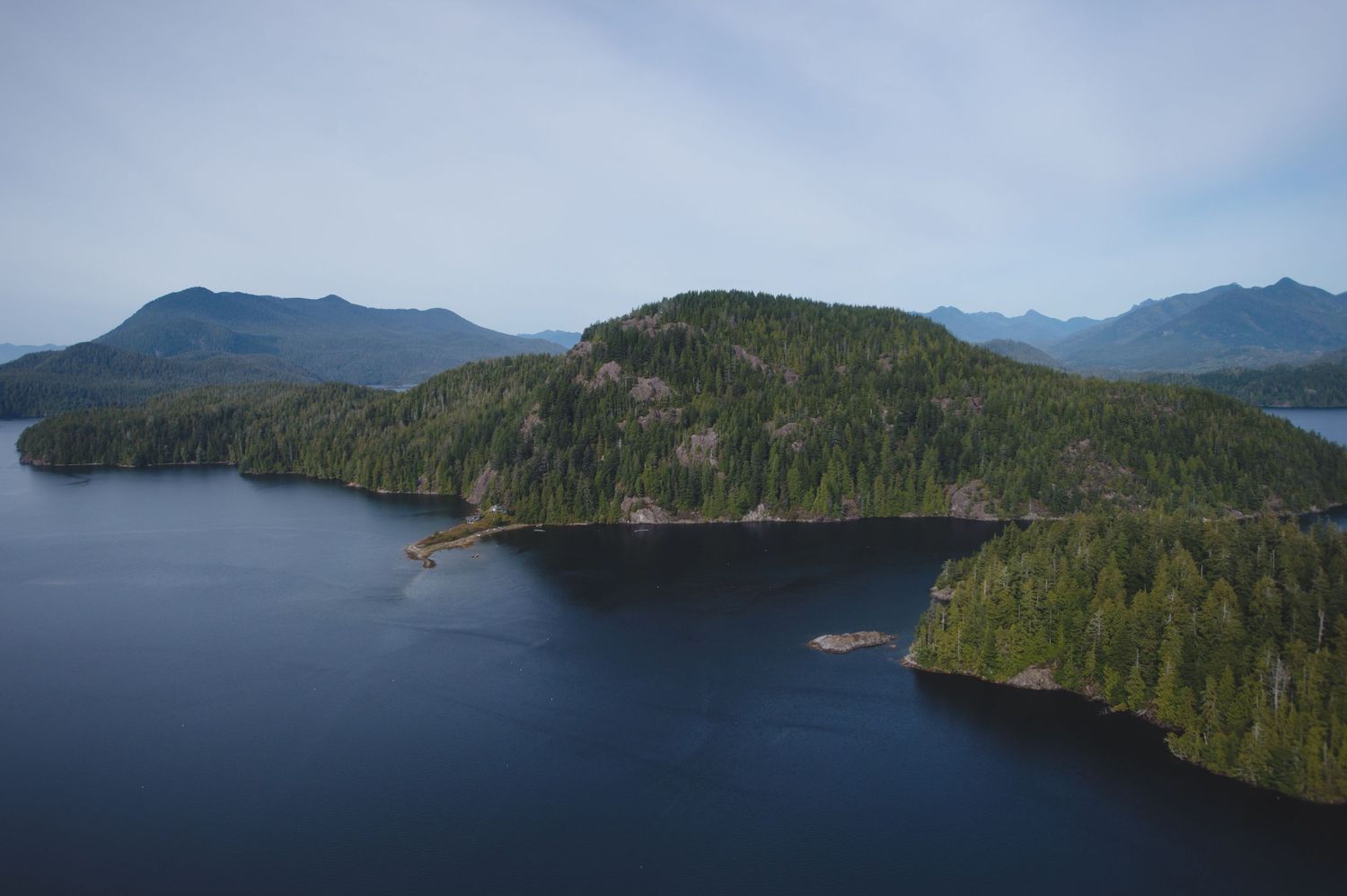 Aerial view of forested islands and inlets along a rugged coastal landscape.