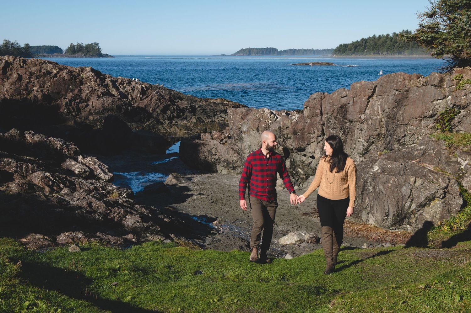 People hiking along rocky coastal cliffs overlooking blue ocean waters.