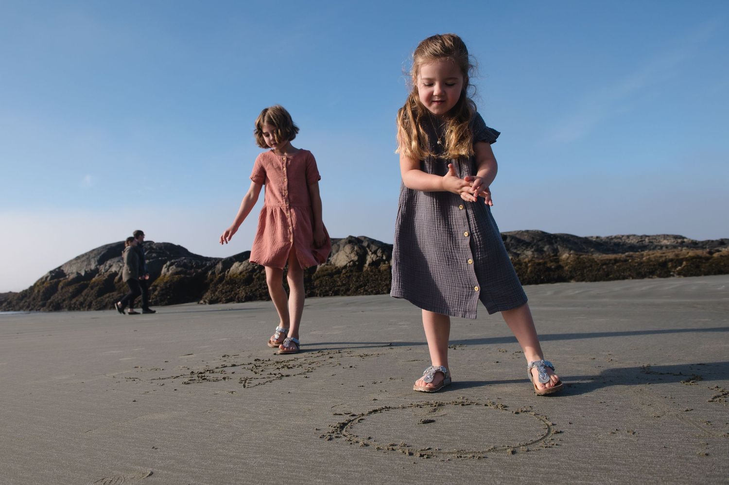 Family creating art together in the sand on a beautiful beach at sunset.