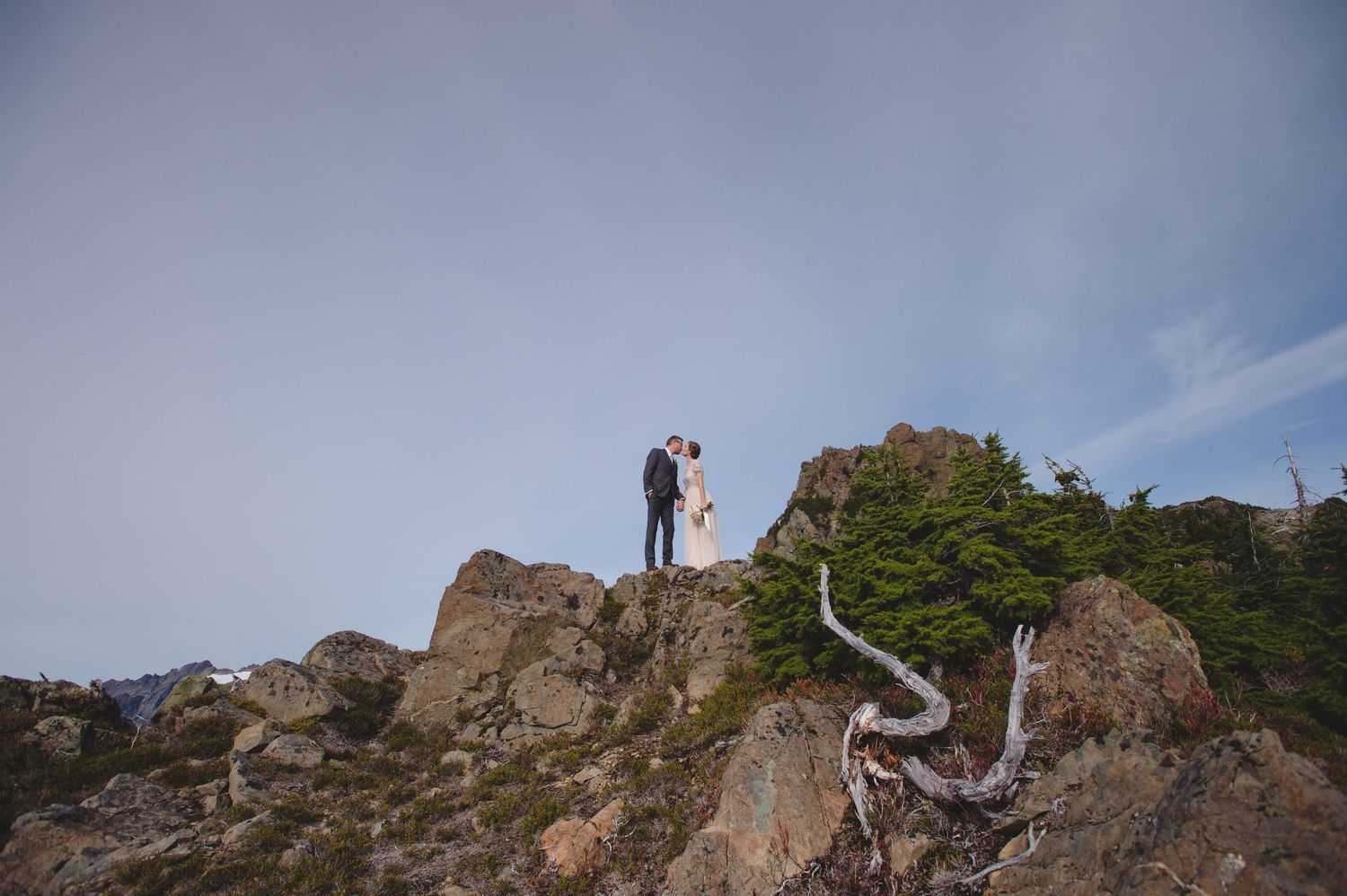 Distant view of a wedding ceremony taking place on a rocky mountain overlook.