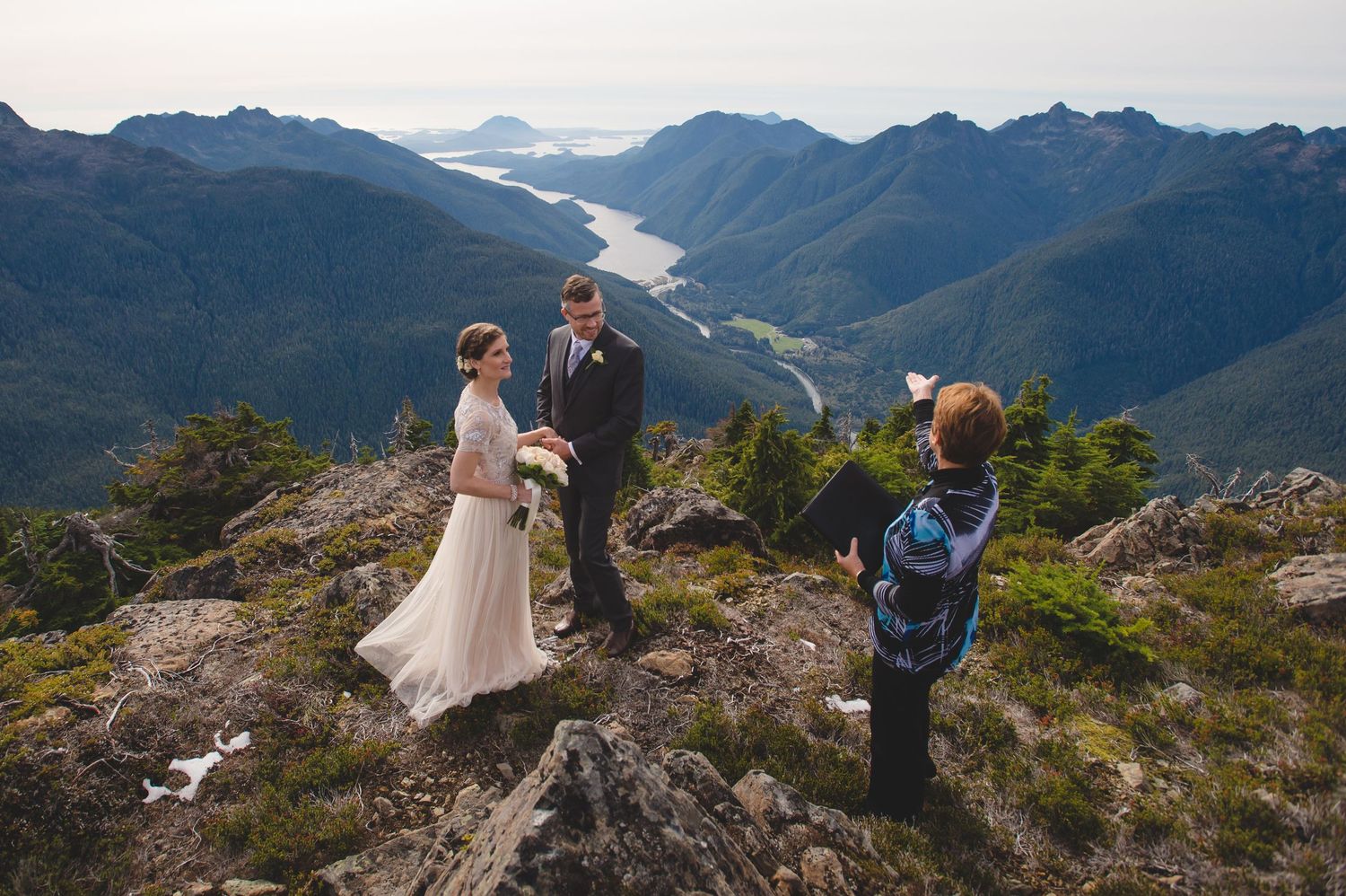 Wedding portraits captured on dramatic mountain peak with sweeping valley views.