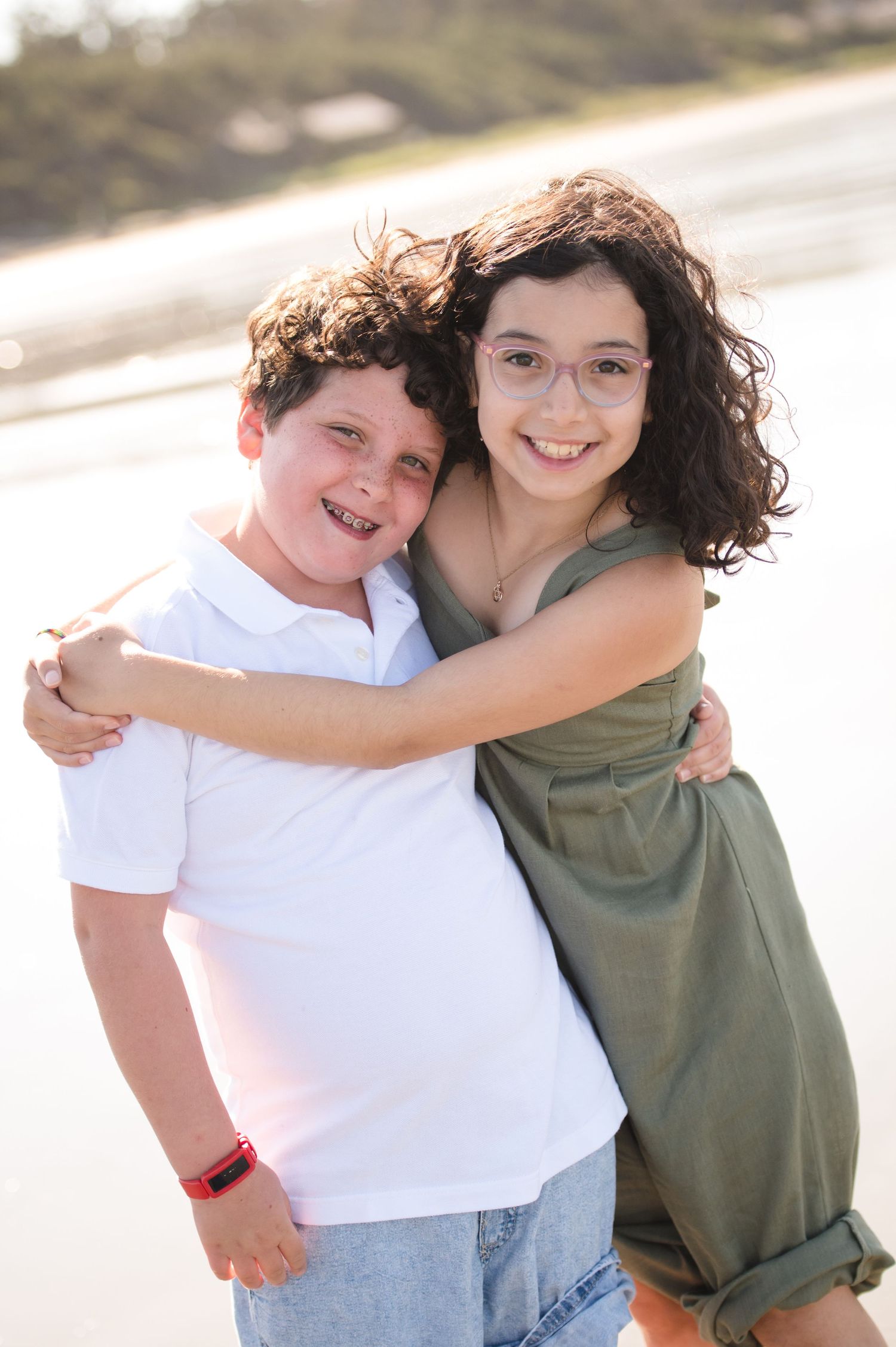 Two people sharing a warm embrace on the beach with natural lighting.