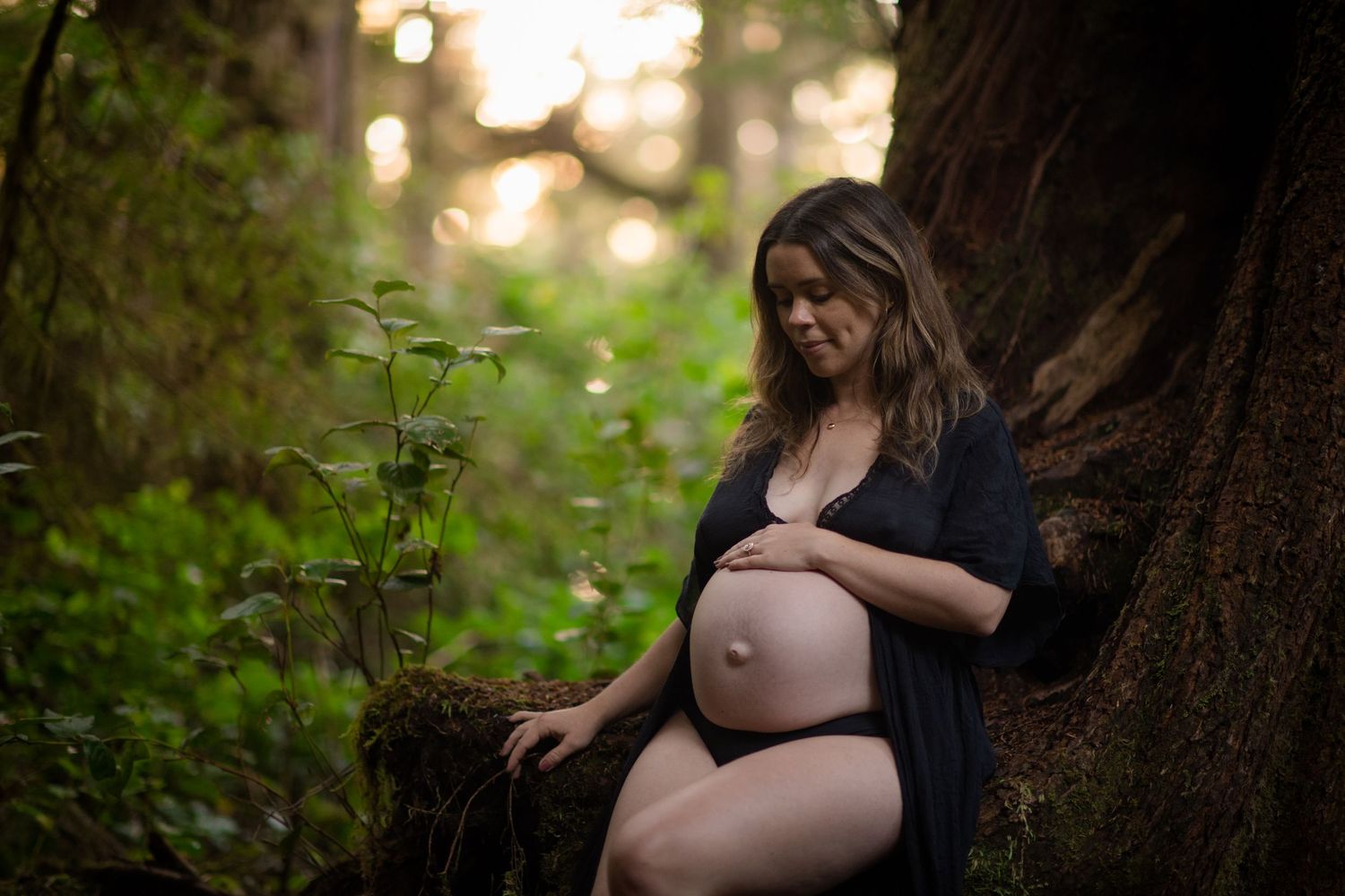 Artistic maternity photo shoot in a mystical forest setting.