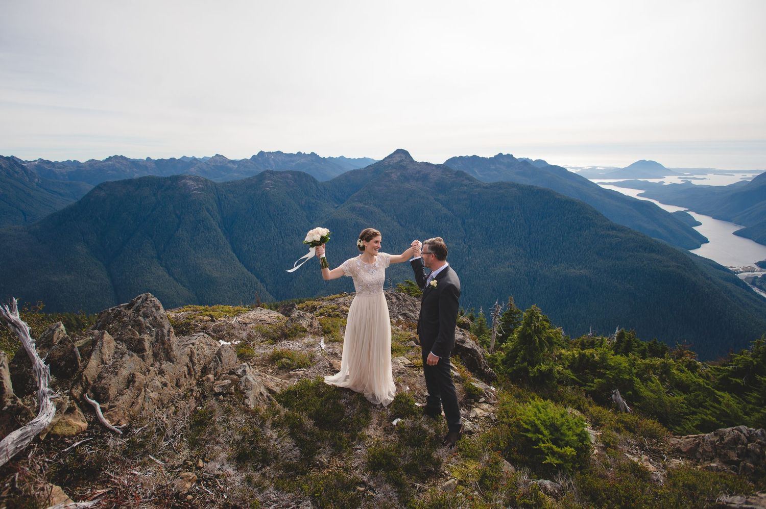 Wide angle view of a mountain wedding ceremony with dramatic coastal landscape.