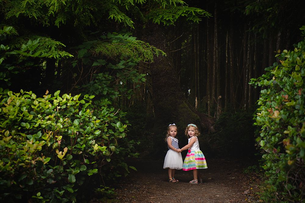 A couple in formal wedding attire stands together in a lush green forest setting during their outdoor photo session.