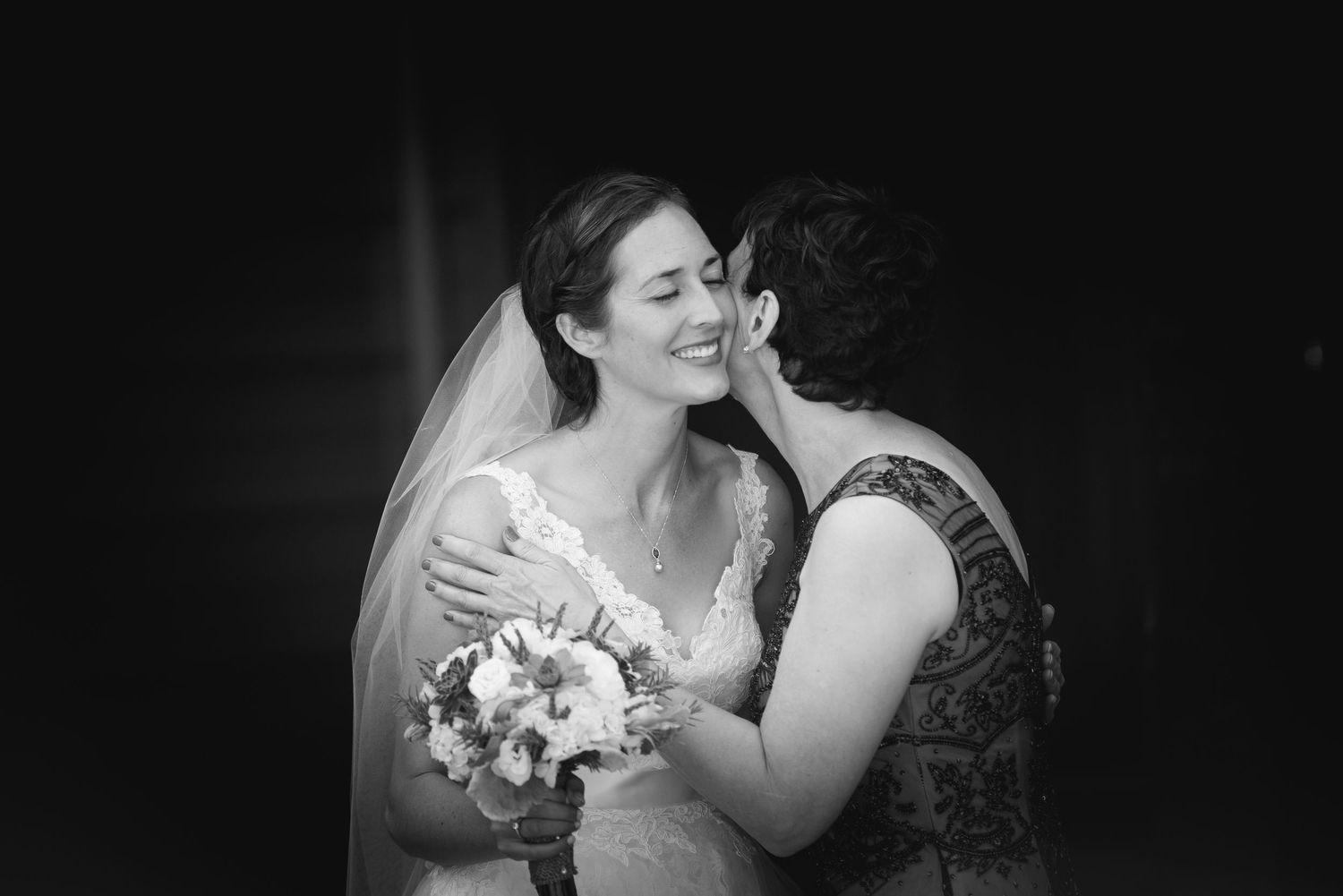 Intimate black and white wedding portrait with dramatic lighting.