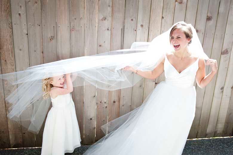 Playful wedding portraits against a rustic wooden wall backdrop.
