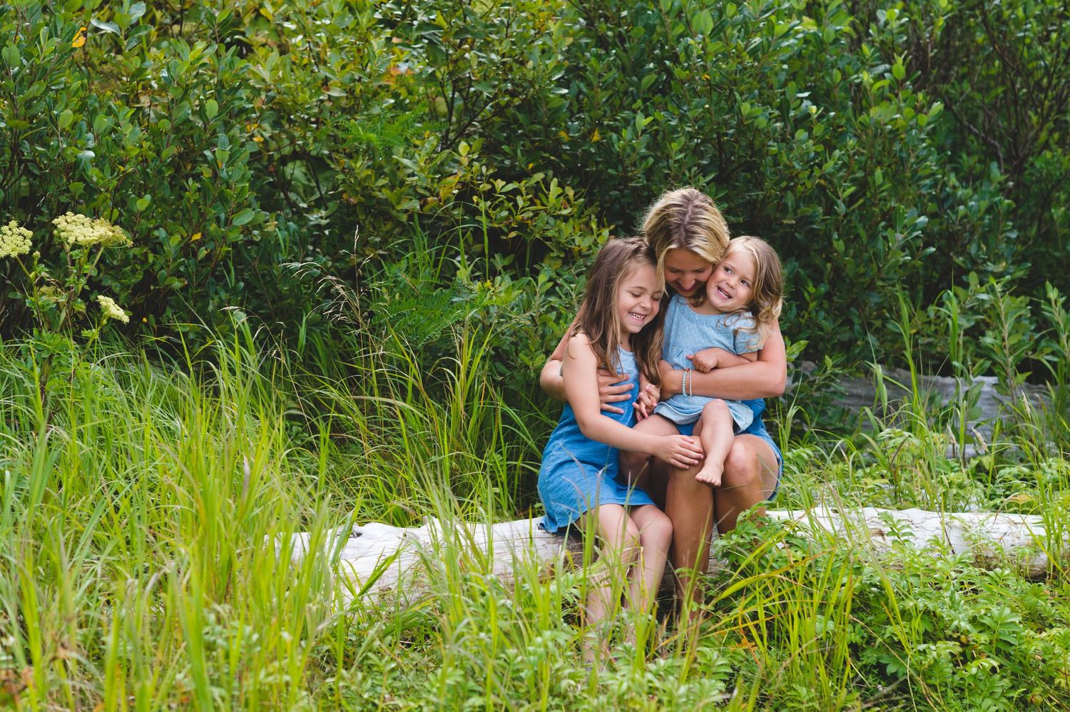 Group enjoying a relaxing summer day sitting together on a white blanket in lush green grass.