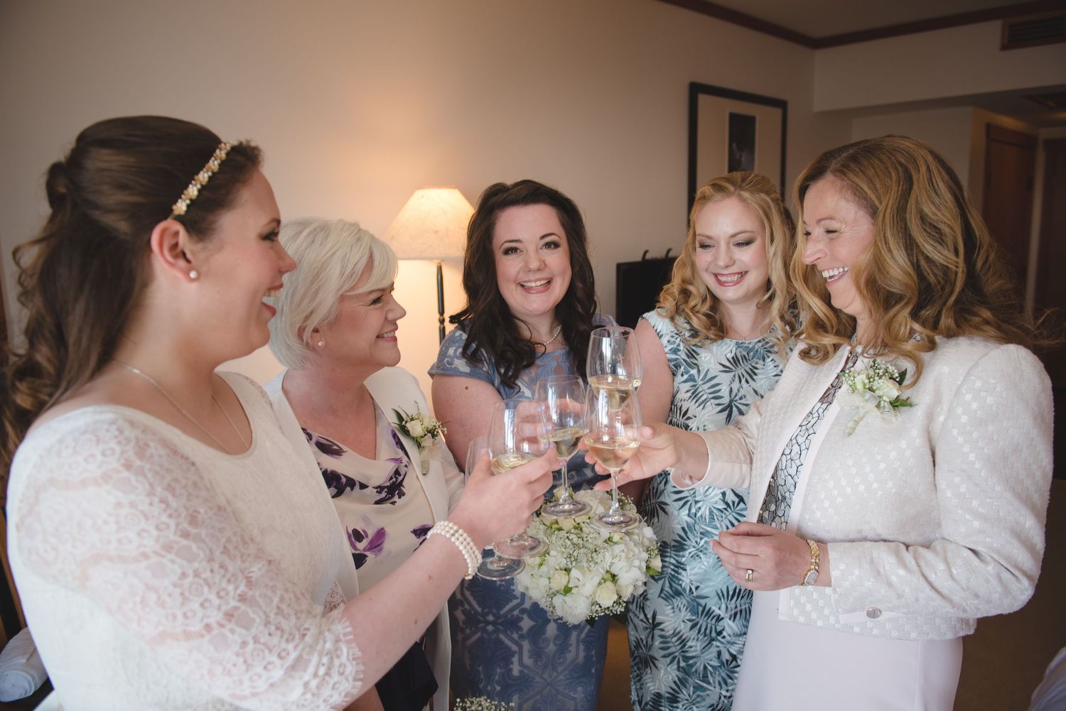 Wedding party members celebrating and toasting with drinks indoors.