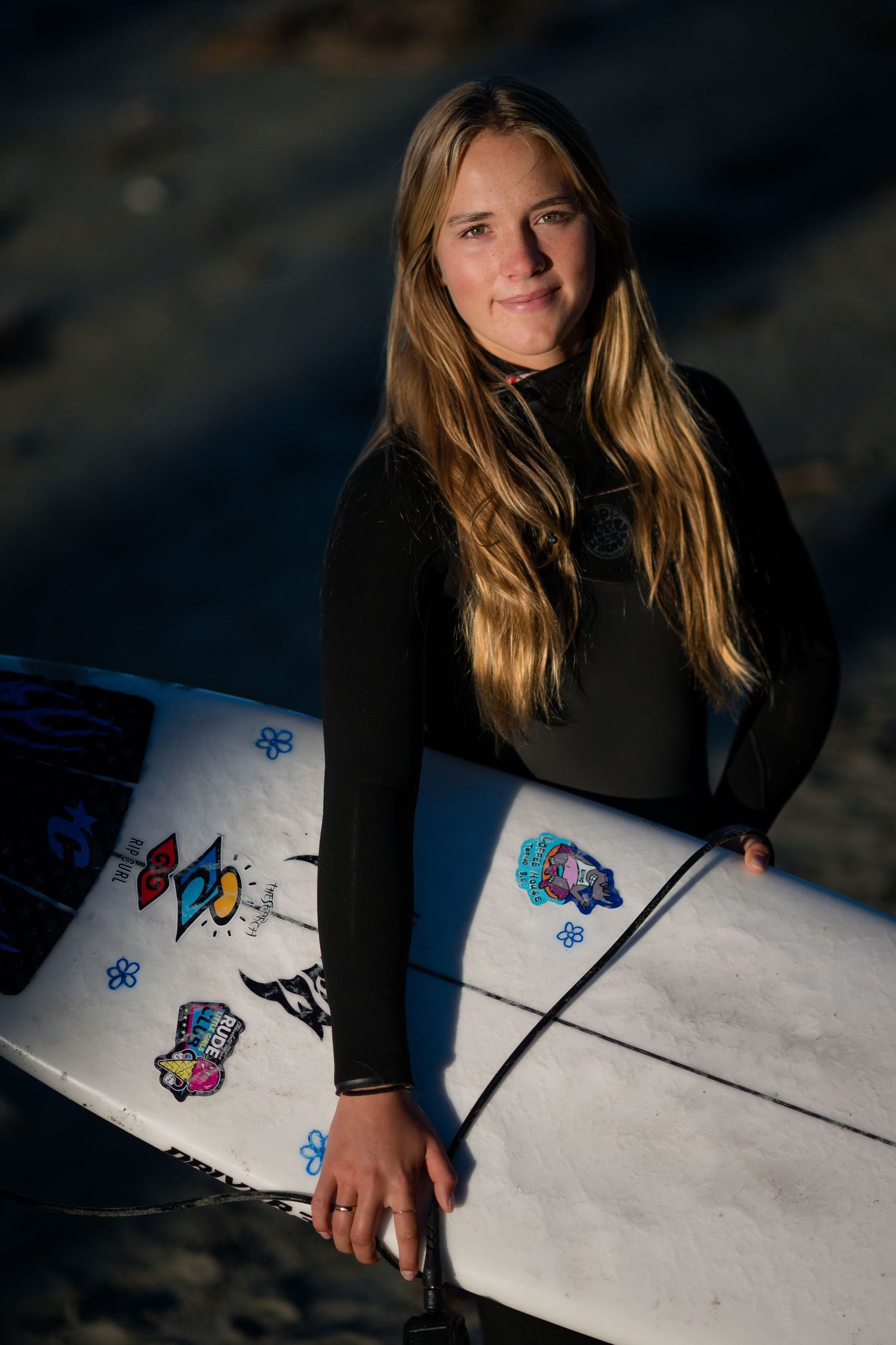 Artist with long blonde hair sketches colorful butterfly designs on white paper in dramatic lighting.
