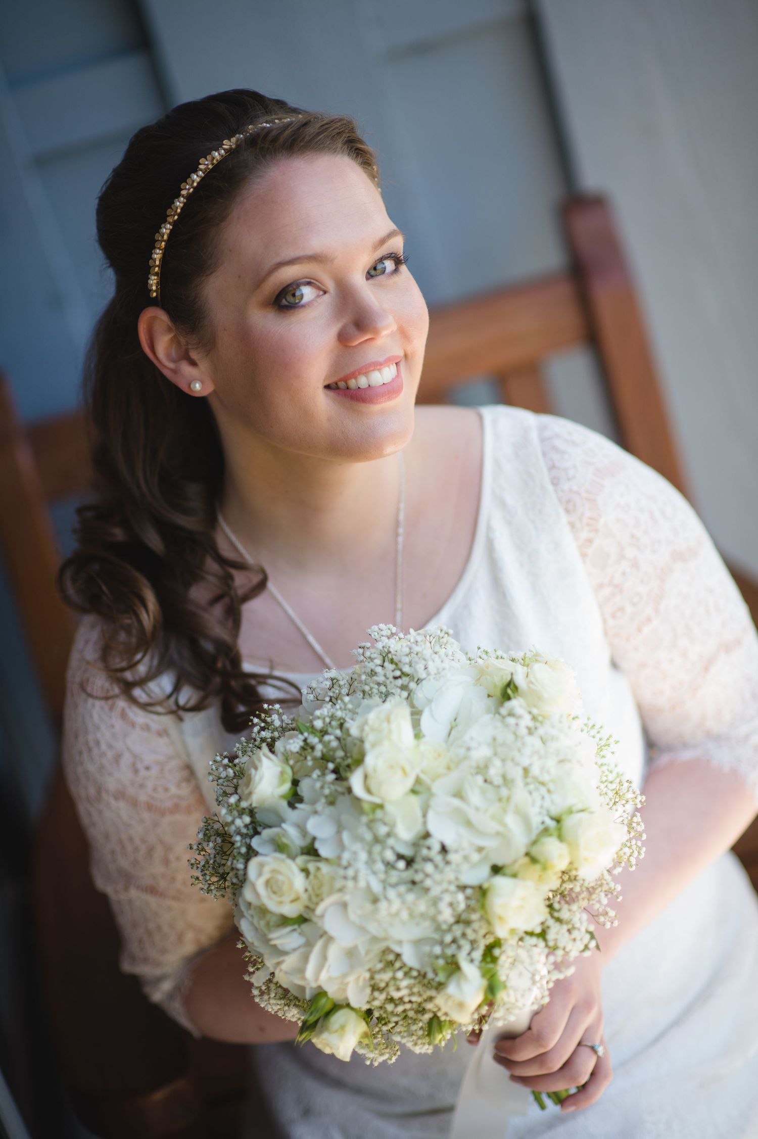 A bridal portrait series showing a white lace dress and delicate bouquet of white roses and baby's breath.