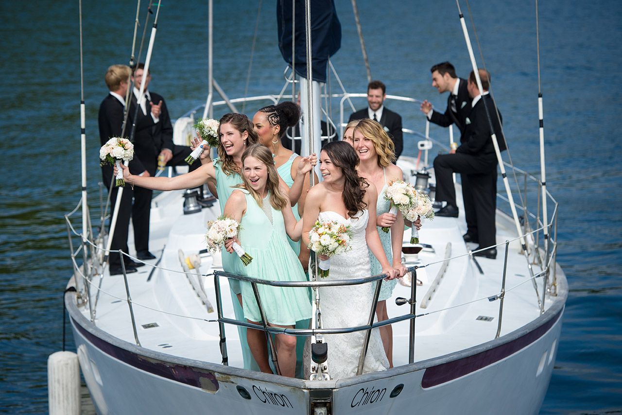 Wedding party celebrating on a sailboat in bright blue waters.