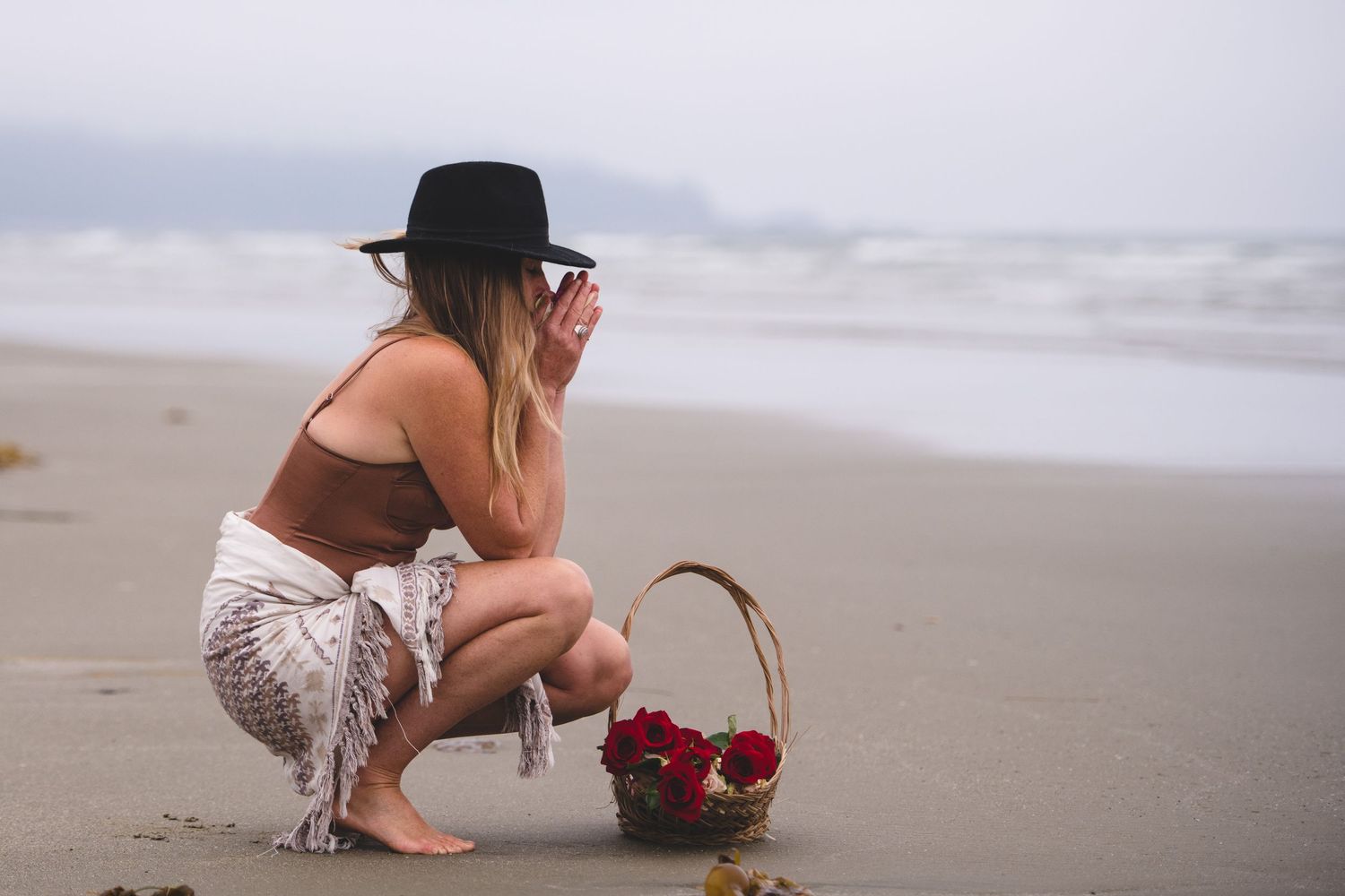A collection of images showing someone scattering red rose petals on a sandy beach at sunset.