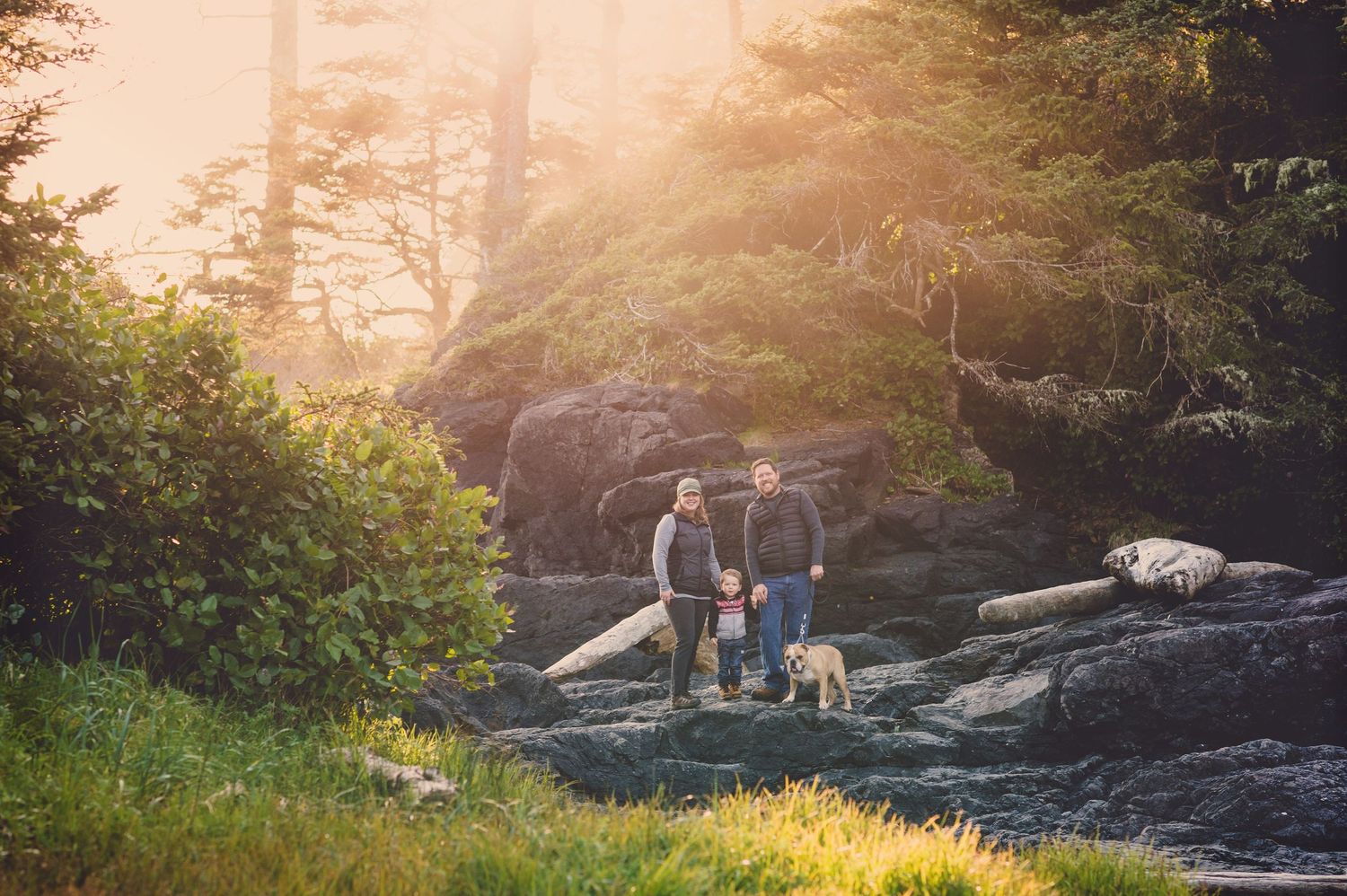 Golden sunset illuminates a rocky coastline with silhouettes of people in the distance.