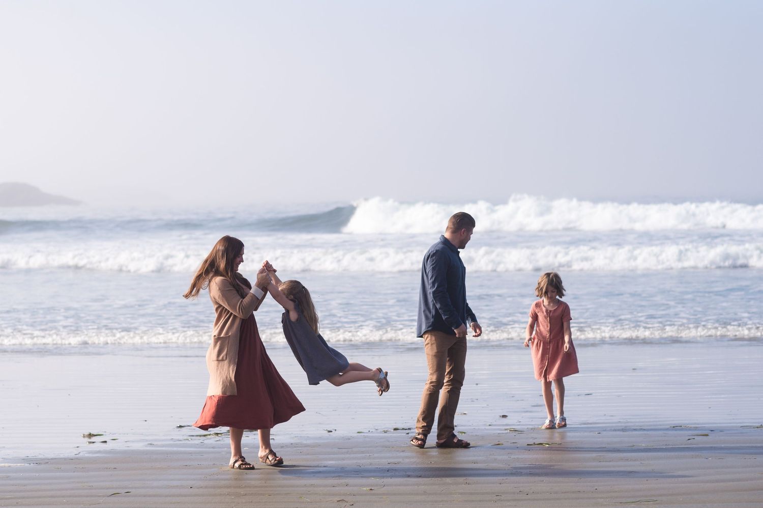 Family enjoying playful moments together on a sunny beach.
