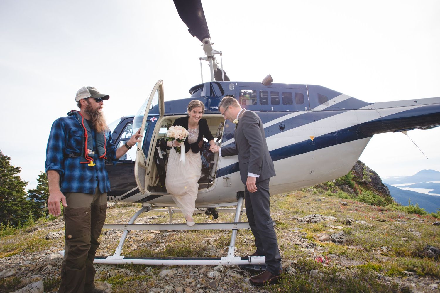 Small helicopter parked on a rocky mountain summit with scenic views.