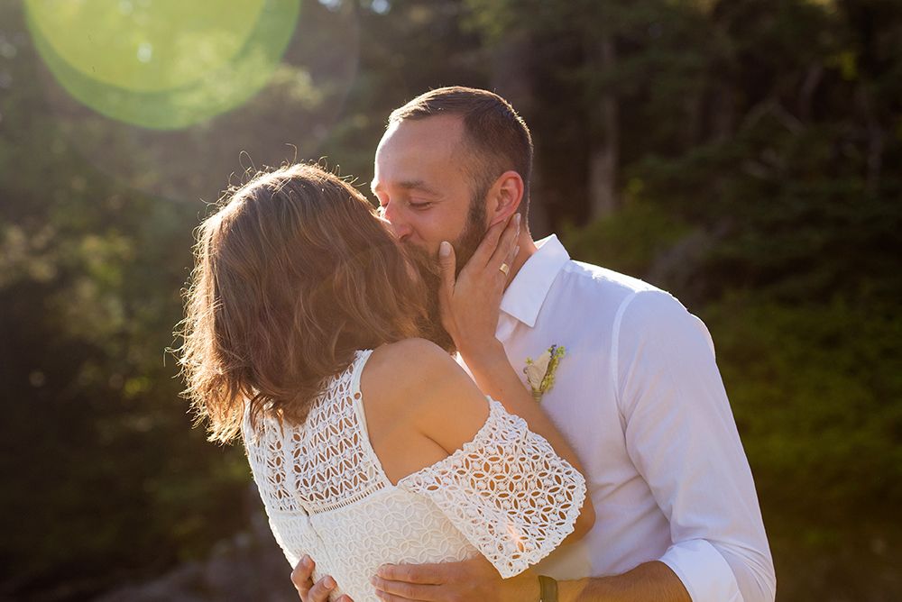A couple in white outfits dancing together in a sunlit outdoor setting during a romantic photoshoot.