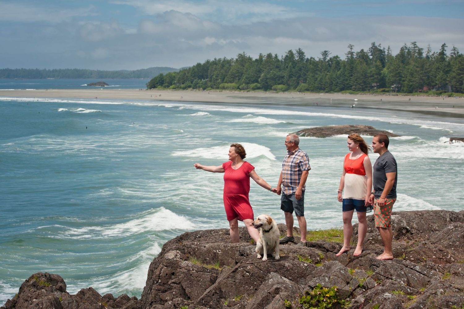 Group enjoying scenic views of rocky coastline and crashing waves at a Pacific Northwest beach.