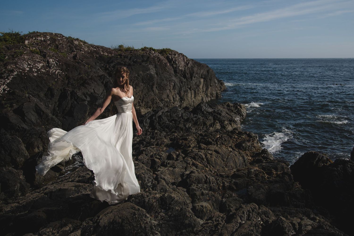 Dramatic coastal wedding photos with rocky cliffs and crashing waves.