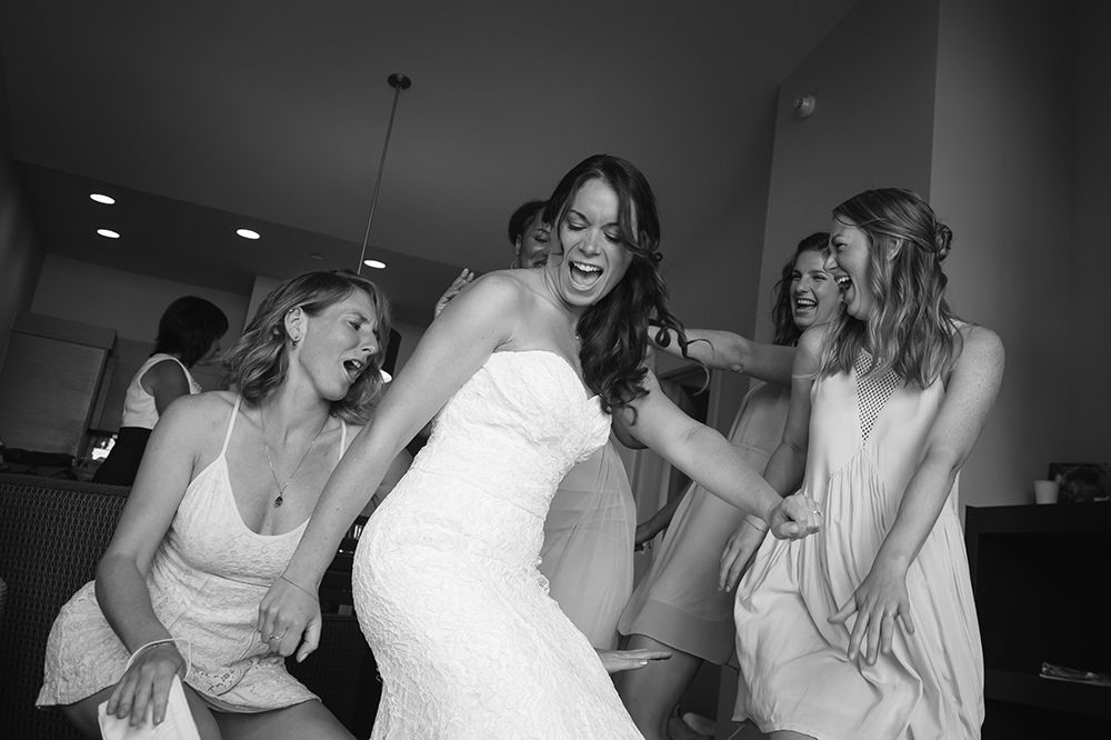 Energetic dance floor celebration with bridesmaids in white and gray dresses.