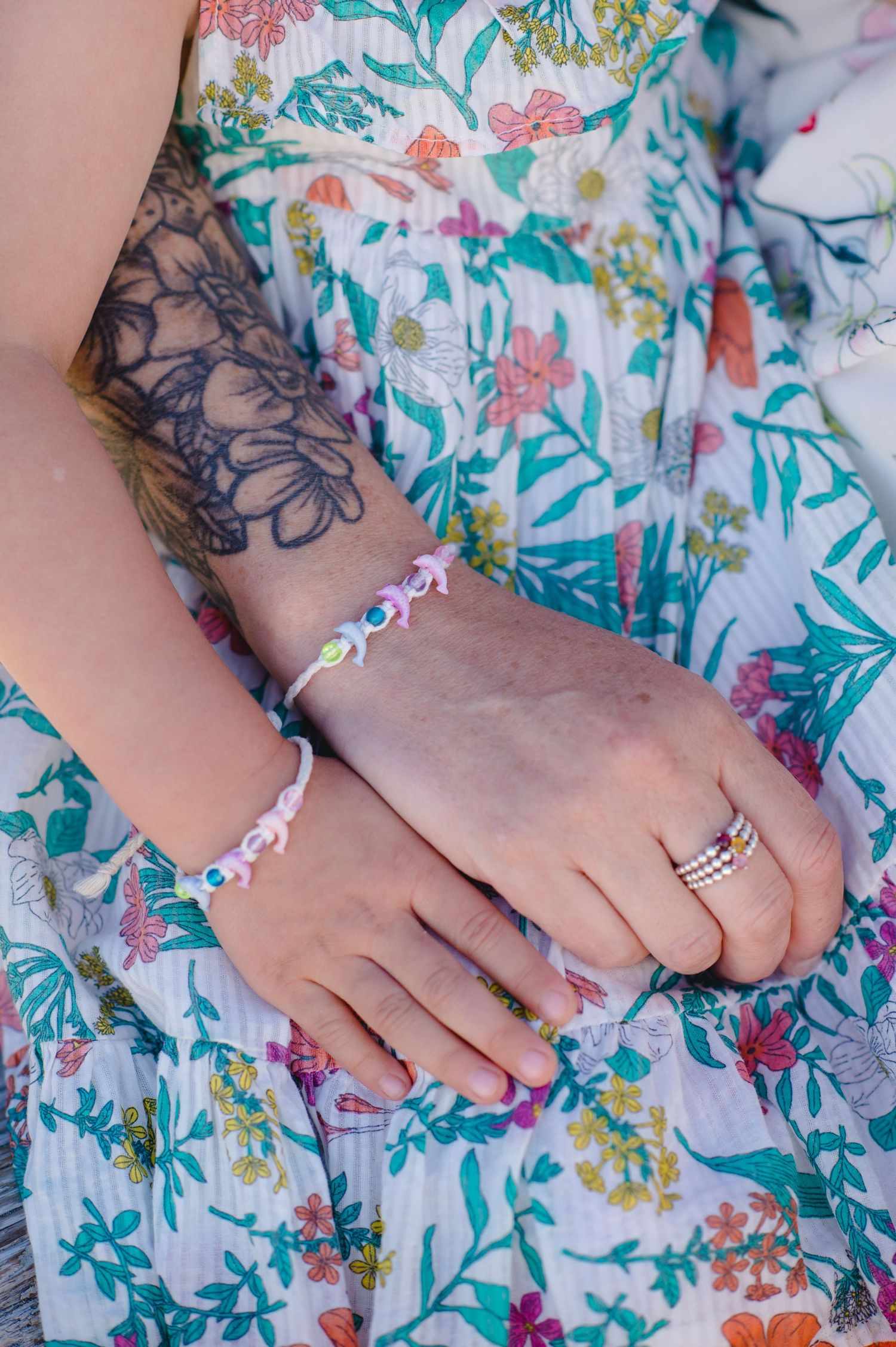 Close-up details of delicate jewelry and floral dress fabric patterns in sunlight.