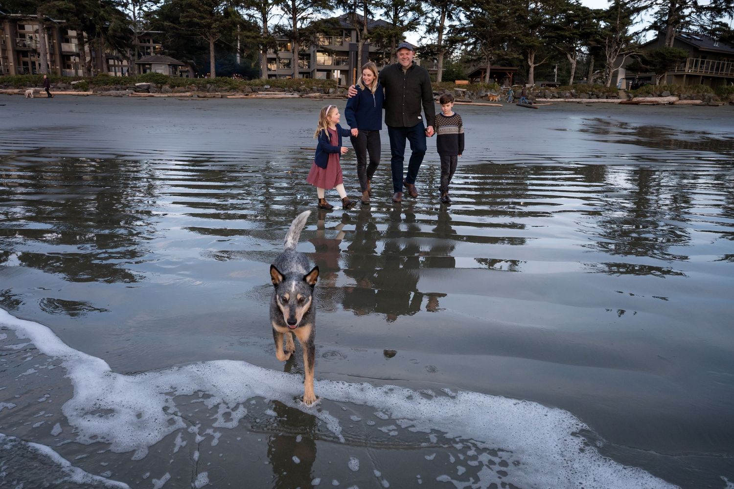 Group walking along a wet sandy beach with waves and reflections.