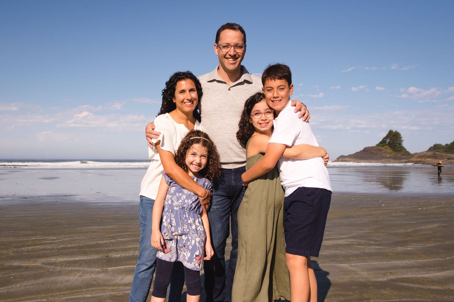 Candid family moments captured on a wide sandy beach with coastal scenery.