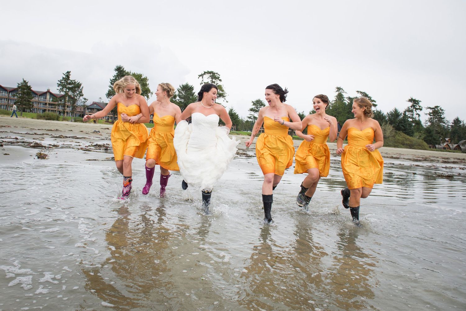 Group wearing bright orange rain gear walking together in shallow ocean water.
