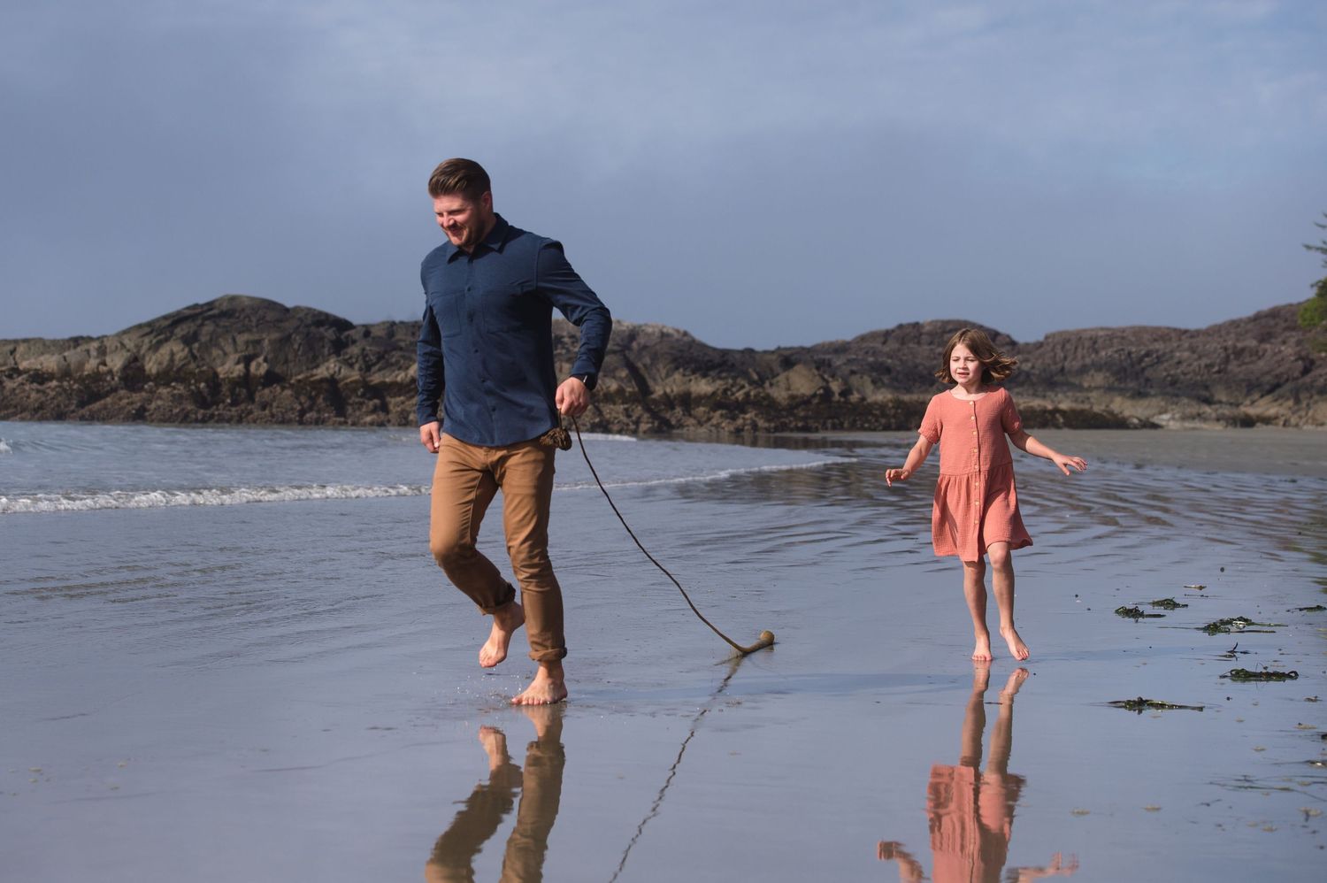 Family enjoying a playful moment at the beach near rocky outcrops.