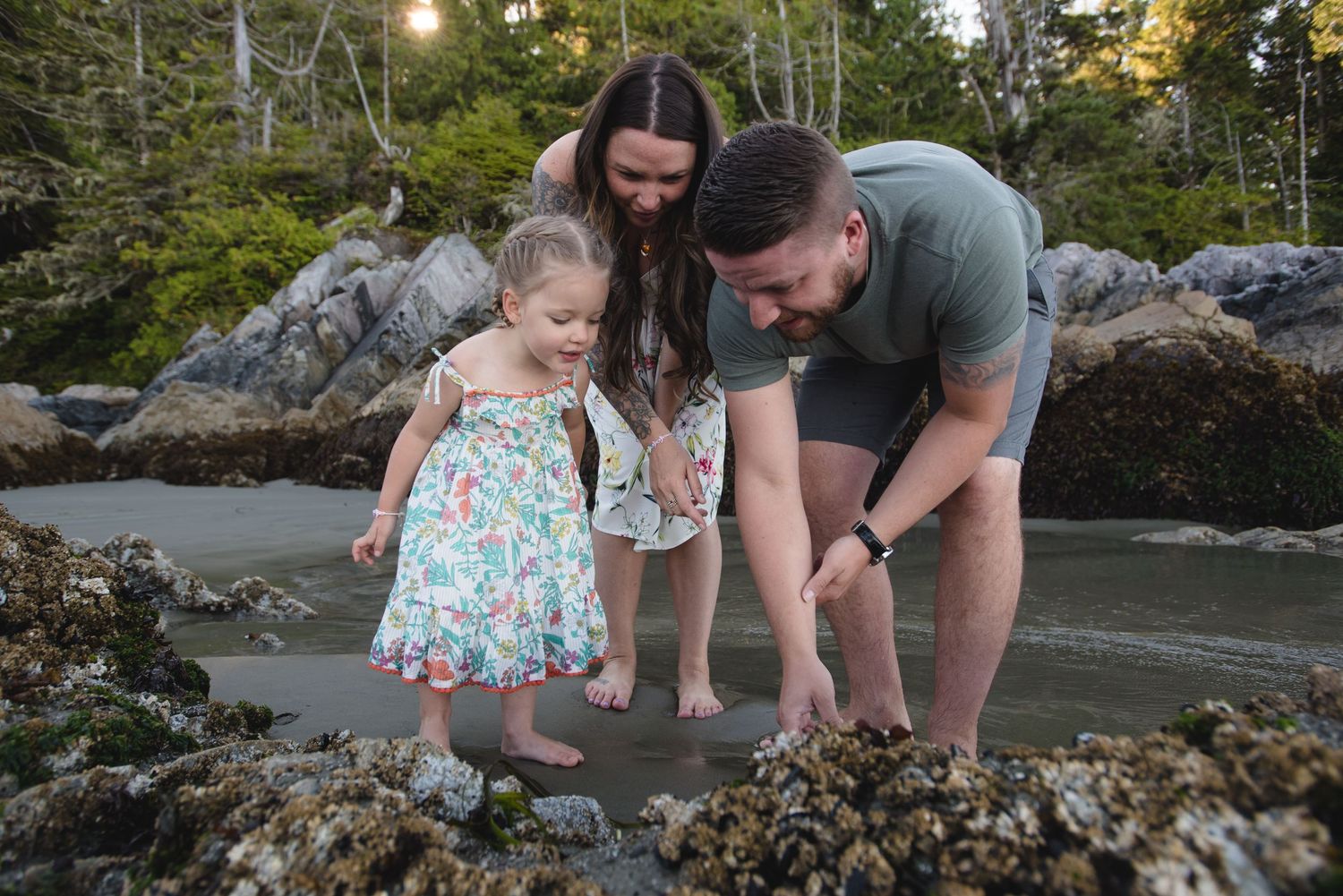 A family discovering beach treasures together among coastal rocks.