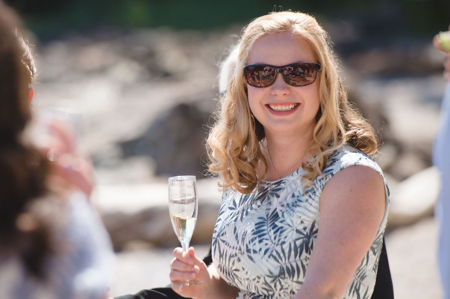 Wedding guests enjoying drinks and conversation at an outdoor beach reception.