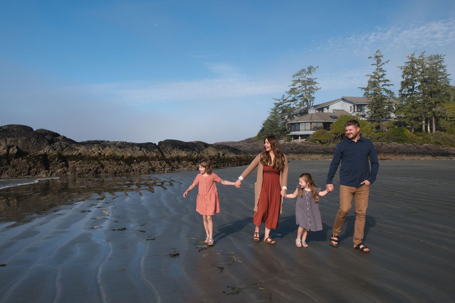 Family walking together along a scenic beach shoreline at sunset.