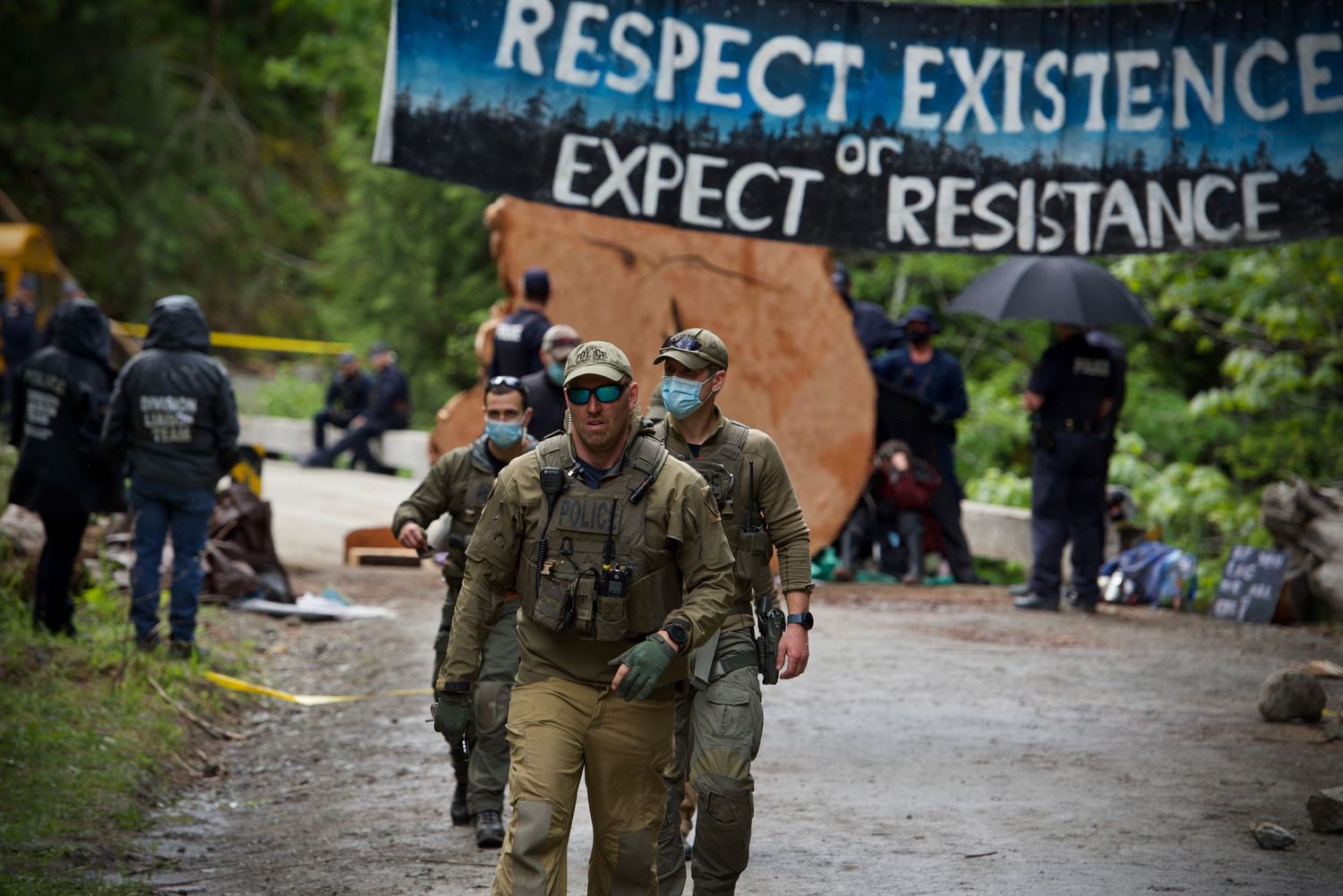 Fairy Creek blockade. Police officers in tactical gear walking through a protest camp area.
